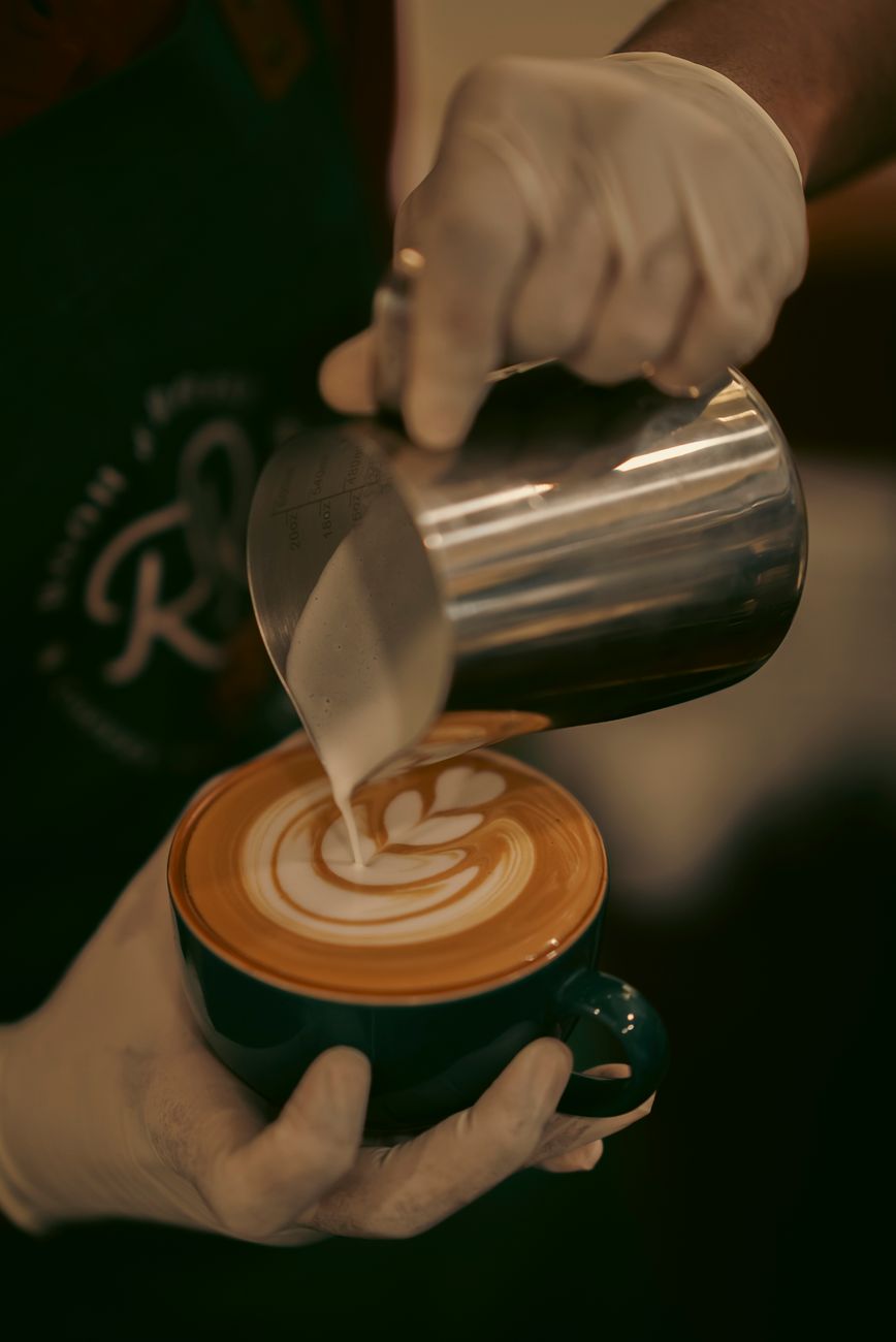 Barista gießt Milch in eine Tasse für Latte Art